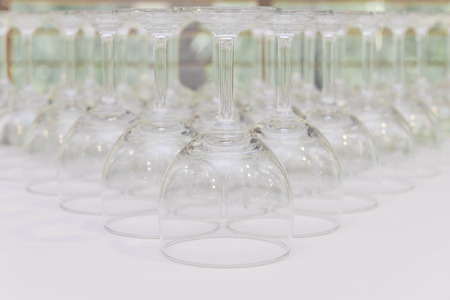 rows of Empty wine glass bottoms on white table.