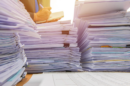 documents on desk stack up high waiting to be managed.