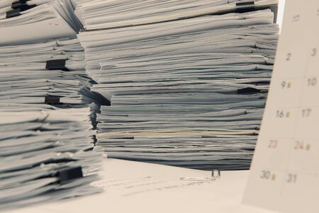 documents on desk stack up high waiting to be managed.の写真素材