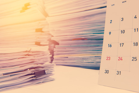 documents on desk stack up high waiting to be managed.