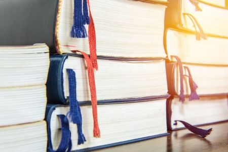 Many books pile on wooden table at library.