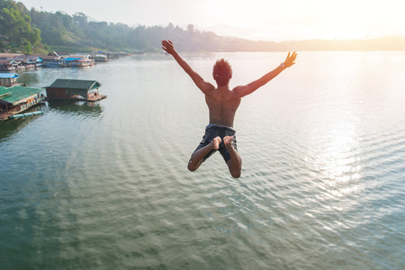 Man jumping into lake retro on Longest wooden bridge in sangkhlaburi Thailand.の写真素材