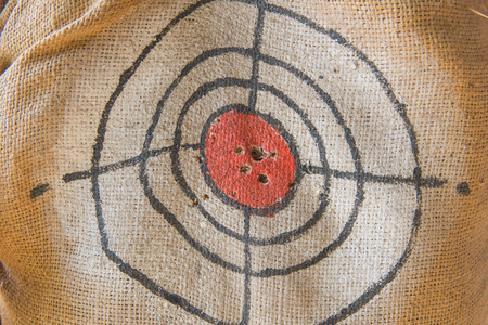 Target gun with bullet holes over sack background.の写真素材