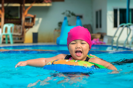 Cute girl or little child playing in swimming pool happily.
