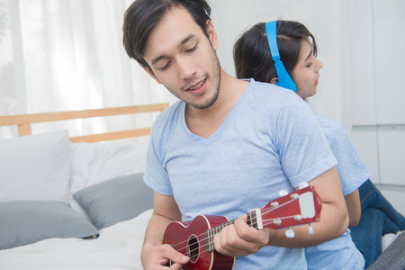 Couple relaxing with happiness and joyful and play ukulele song in bedroom.の写真素材