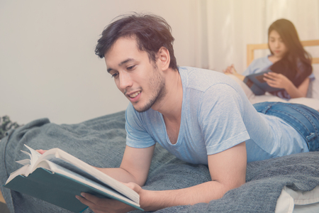 young loving couple reading a book on bedroom at home.の写真素材