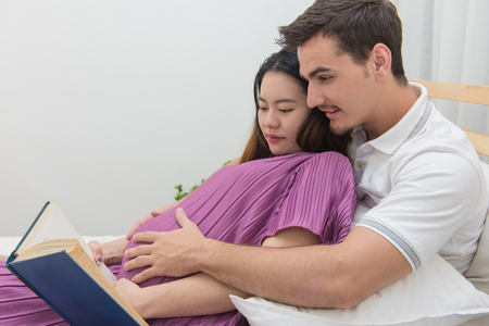 pregnant woman and her handsome husband reading a book.の写真素材
