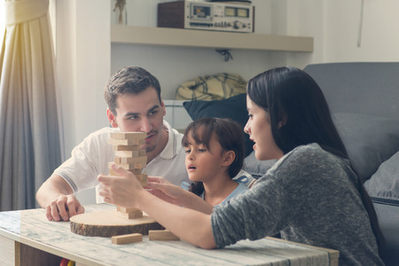 happy family and Daughter playing the wooden blocks tower at home.の写真素材