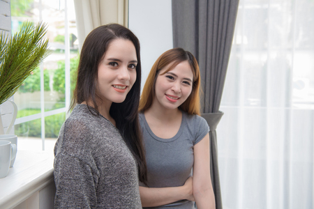Portrait of two young woman standing in living room at home.の写真素材
