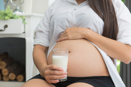 pregnant woman Holding a glass of fresh milk for healthcare.の写真素材