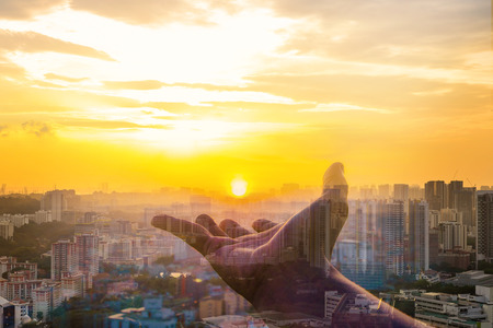 Double exposure of Hand holding sunset on cityscape background.の写真素材