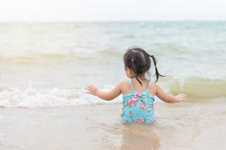 little girl sitting and playing on the beach with sand.の写真素材