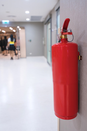 Fire extinguisher on wall in front of room at building.の写真素材