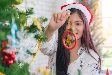 Beautiful young woman decorating xmas ornament on  Christmas tree for Christmas and New Year holiday.の写真素材