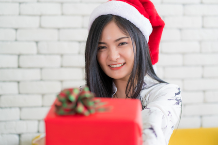 Happy woman wearing santa hat holding a gifts in Christmas and New Year holiday.の写真素材
