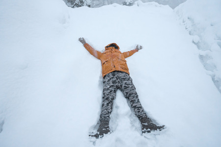 happy man lying down on the snow in winter.