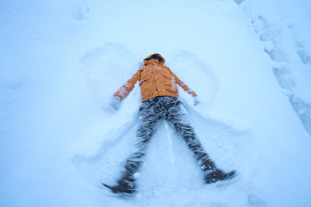 happy man lying down on the snow in winter.の写真素材