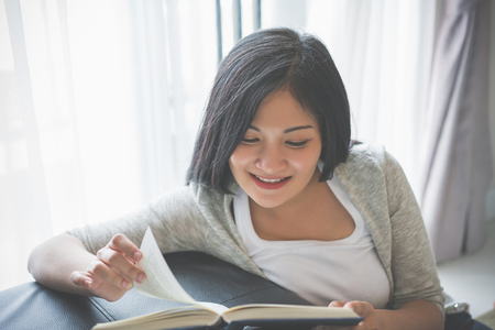 Young woman reading a book on bed at home.の写真素材