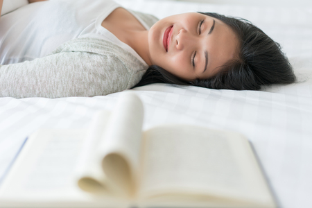 Beautiful woman sleeping on the bed sleeping after reading a book overnight.の写真素材