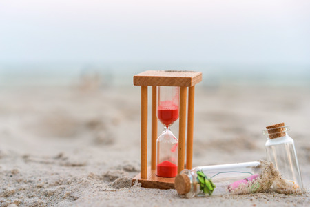 Message or letter in bottle with hourglass on the tropical beach.