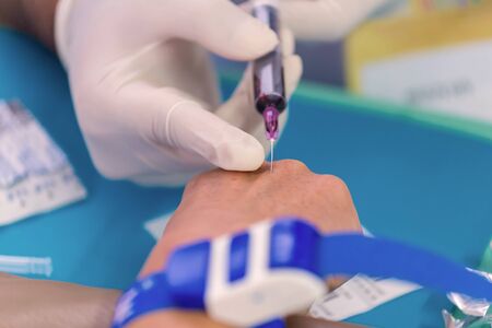 Nurse collecting a blood on hand from patient in hospital.の写真素材