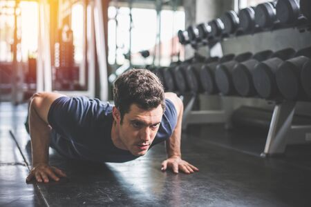 Handsome man and strong guy doing push ups exercise in fitness gym.