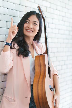 young woman playing guitar in living room, Enjoying carefree time at home.の写真素材