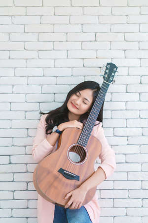 young woman playing guitar in living room, Enjoying carefree time at home.の写真素材