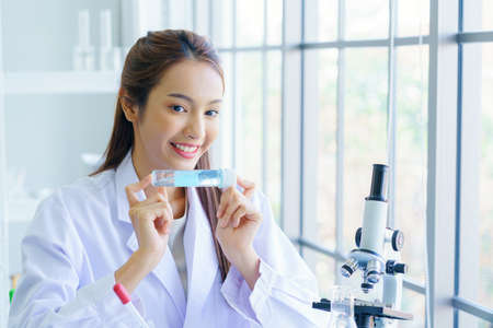 scientist woman lab technician assistant showing alcohol hand gel for cleaning hands at laboratory, Doctor and microbiologist with vacuum tubes for samples Virus resistance concept.の写真素材