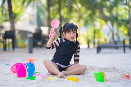 adorable child girl with sand toys in sandbox. Outdoor creative activities for kids.の写真素材