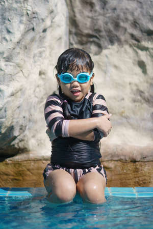 Cute girl with goggles having fun in summer in the pool summer vacation concept.