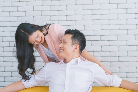Happy couple Boyfriend sitting on sofa and Girlfriend is giving her shoulder massage after Business...