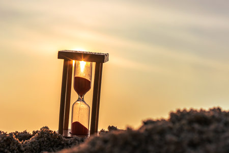 Time concept Hourglass on sandy beach in summer with sea background.の写真素材