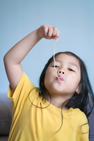 Happy Child or Little girl eating delicious noodle, kid have fun and joyful with eating.の写真素材