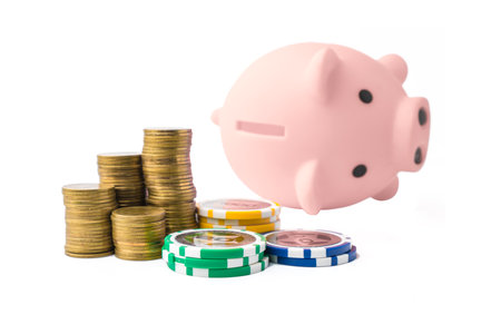Piggy bank and money coins stack with casino chips on white background. Concept of gambling savings.の写真素材