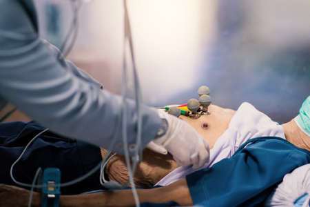 ECG or EKG of man with electrodes for electrocardiogram records on bed in hospital