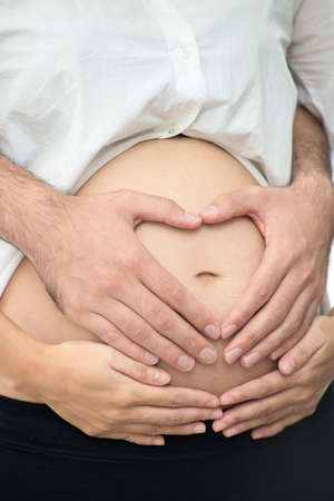 Pregnant woman with husband or parents hands on pregnant belly  Love couple using their hands to...