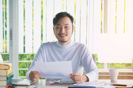 Business man working with laptop computer and documents on his desk at office.