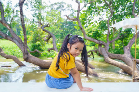 Asian child cute or kid girl sitting near the river or public park,  country trip concept travel day.の写真素材