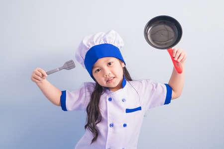 Happy girls with amazing smile in clothes and chef cap. child dreams of becoming a chef.の写真素材