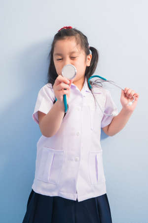 Happy cute girls in white medical uniform and stethoscope over neck act like doctor. child dreams of becoming a doctor career concept.の写真素材
