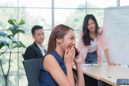 business woman sitting in meeting room at office talking on telephone and ignoring communication with each other for during work meeting.の写真素材