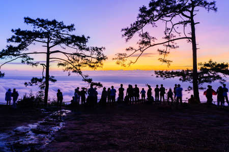 Beautiful Silhouette of hiker or traveler enjoy mist and sunrise at Nok Aen Cliff, Phu of Kradueng national park, Loei, Thailand.の写真素材