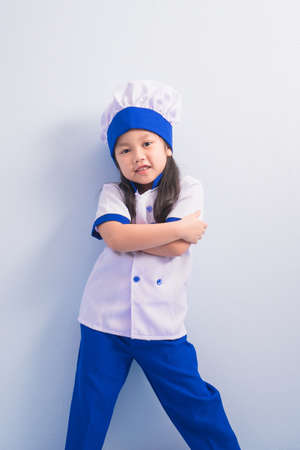 Happy girls with amazing smile in clothes and chef cap. child dreams of becoming a chef.の写真素材
