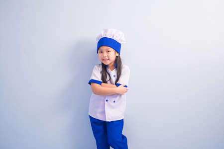 Happy girls with amazing smile in clothes and chef cap. child dreams of becoming a chef.の写真素材