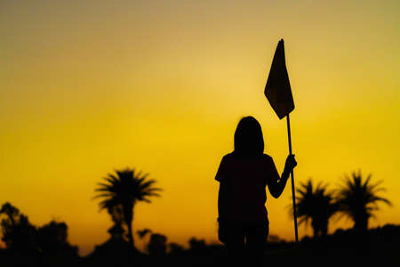 Woman silhouette with sunset over palm trees on the golf course.の写真素材