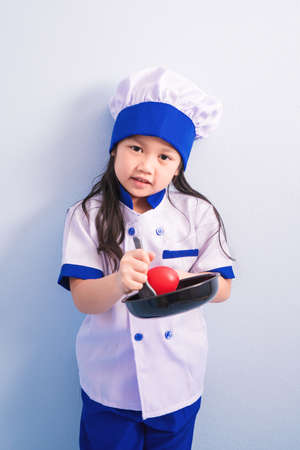 Happy girls with amazing smile in clothes and chef cap. child dreams of becoming a chef.の写真素材