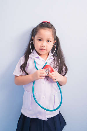 Happy cute girls in white medical uniform and stethoscope act like doctor. child dreams of becoming a doctor career concept.の写真素材