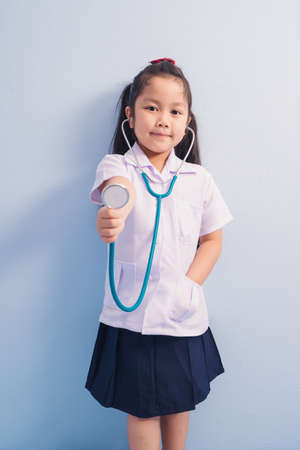 Happy cute girls in white medical uniform and stethoscope act like doctor. child dreams of becoming a doctor career concept.の写真素材