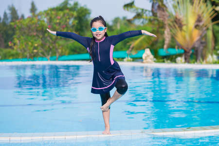 little girl smiling wearing swimming glasses in swimming pool. children playing in swimming pool on summerの写真素材